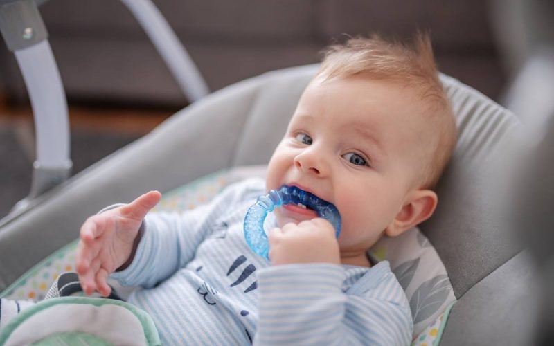 baby with a teether in a swing